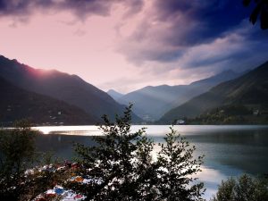 Tramonto sul lago di Garda tra le fronde degli alberi e le montagne